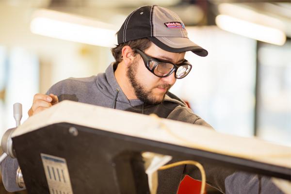 Man wearing safety goggles using mechanical engineering equipment